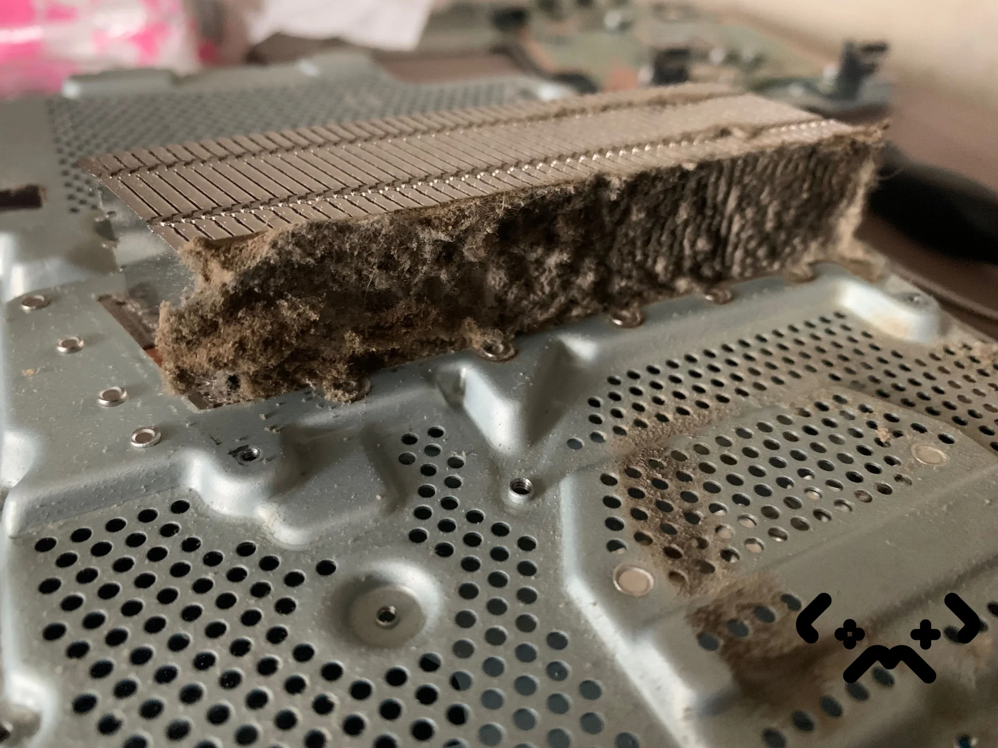 Avattu PS4 Pro työpöydällä, jäähdytysrivat paksun ruskeanharmaan pölykerroksen peitossa.